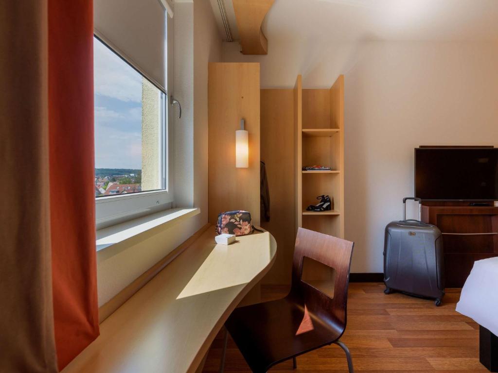 a hotel room with a desk and a window at ibis Stuttgart Airport Messe in Leinfelden-Echterdingen