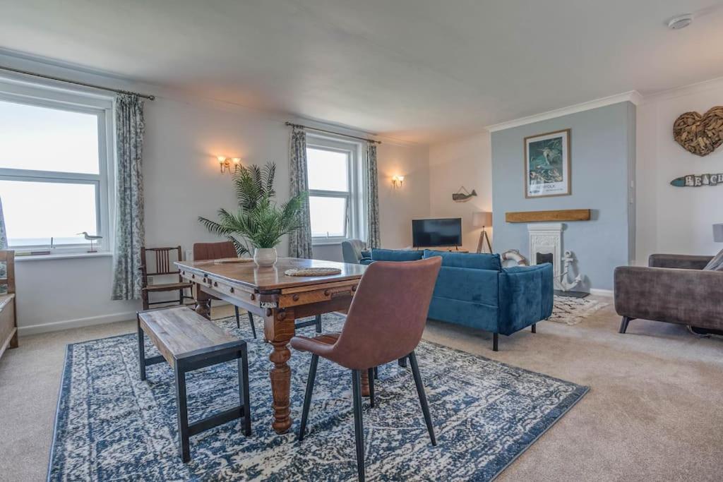 un soggiorno con un tavolo e un divano blu di Seafront Apartment Hunstanton - Crabpot Cottages a Hunstanton