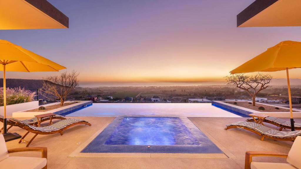 a pool with chairs and umbrellas on a patio at Villa Damiana Boutique Hotel and Villa in El Pescadero