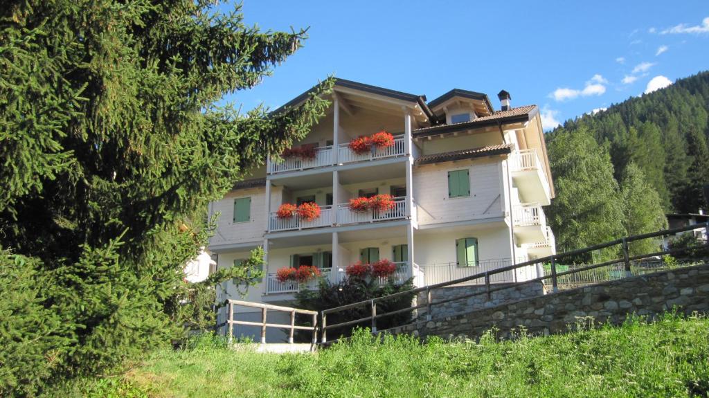 a large building with red flowers on the balcony at VALDISOLE-home in Ossana