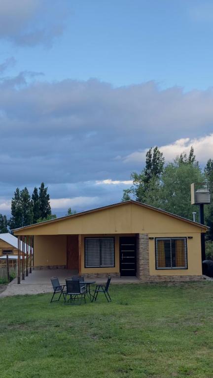 a yellow house with two chairs in front of it at Bella Vista valle del sol potrerillos in Potrerillos
