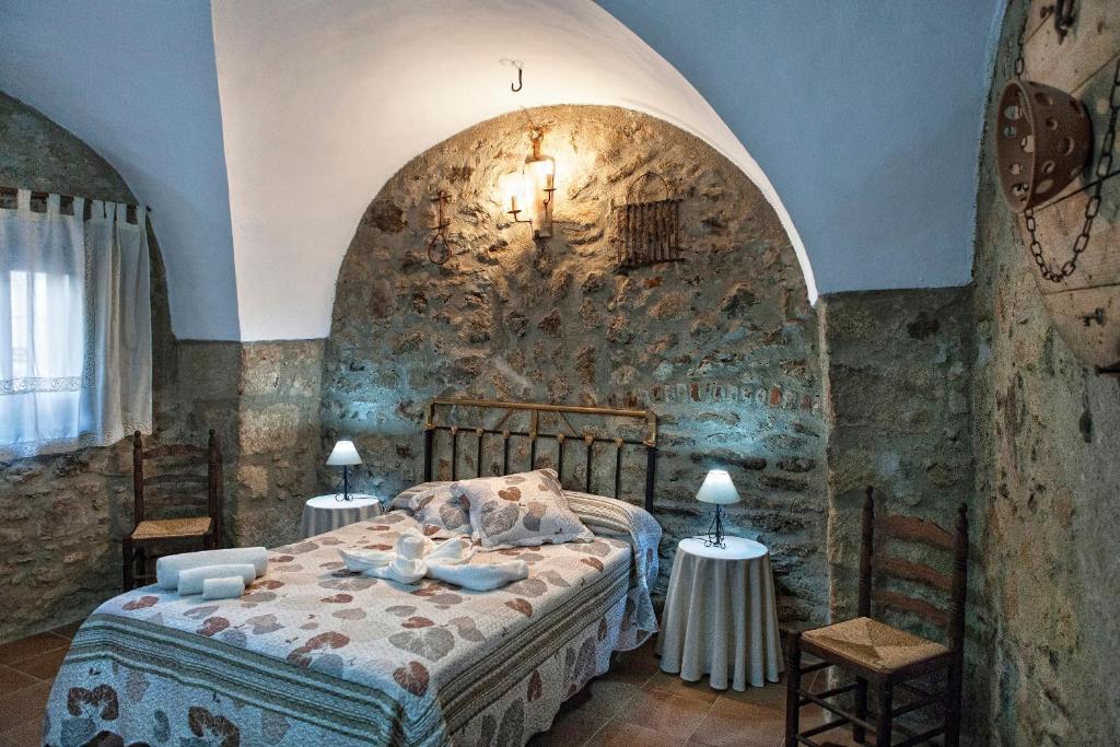 1 dormitorio con 1 cama en una pared de piedra en Apartamentos Rurales La Casa de Luis, en Santa Cruz de la Sierra