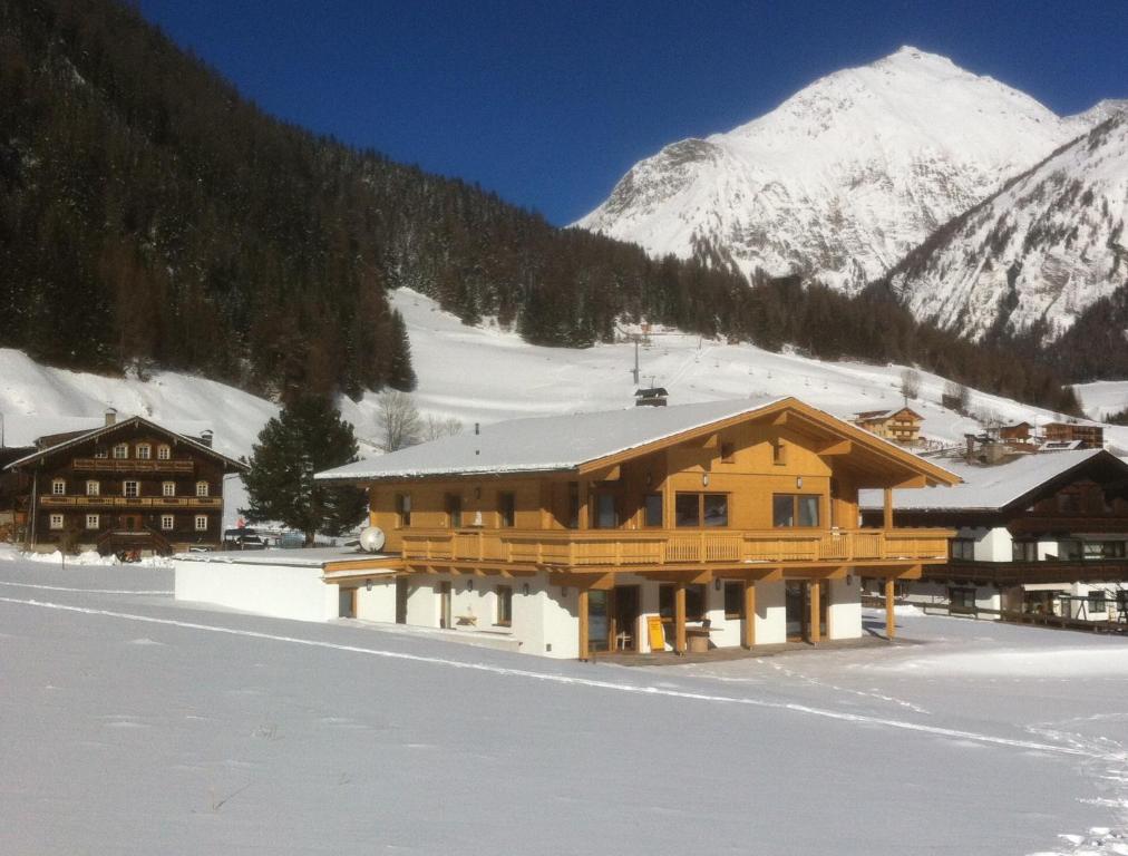 a large wooden building in the snow with mountains at Großglockner Goldried Chalet in Kals am Großglockner