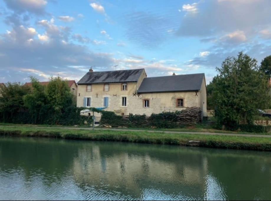 un bâtiment à côté d'un plan d'eau dans l'établissement Maison de charme sur le Canal de Loire, à Bannay