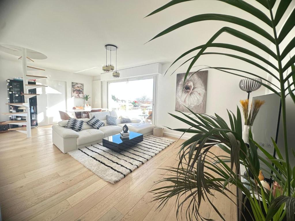un salon avec un canapé blanc et une plante en pot dans l'établissement Appartement Rooftop, à Montmorency
