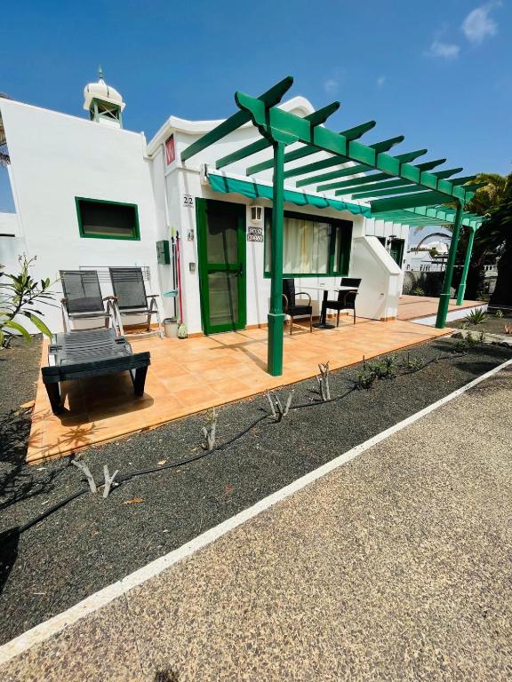 a patio with a green pergola in front of a house at Playa Park in Puerto del Carmen
