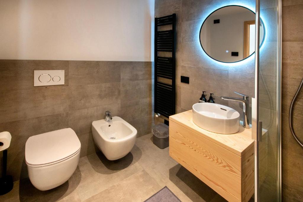 a bathroom with a toilet and a sink and a mirror at BORMIO N'JOY in Bormio