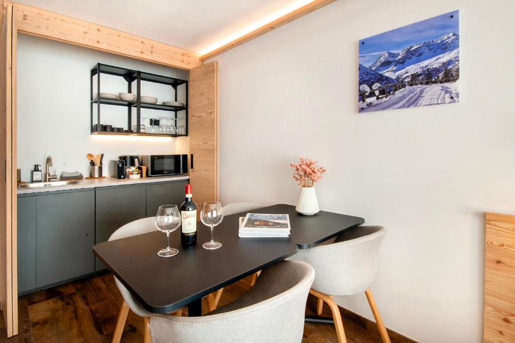 a kitchen and dining room with a black table and chairs at BORMIO N'JOY in Bormio