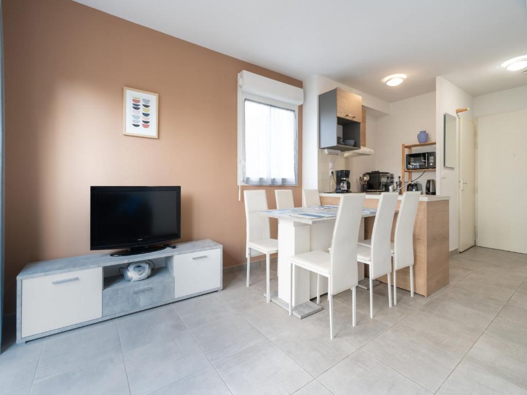 a living room with a television and a table with chairs at La DUNE N 01 - VILLA 3P6 in Valras-Plage