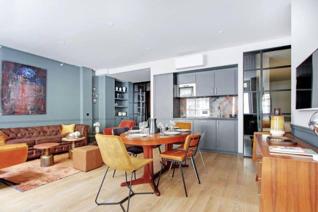 une cuisine et un salon avec une table et des chaises dans l'établissement V Vast Apartment, Steps from Place des Vosges AC, à Paris