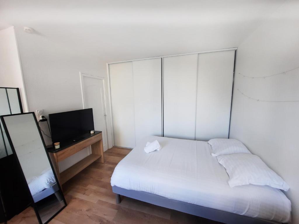 une chambre avec un lit blanc et une télévision dans l'établissement Courtépée - Apt 2 Prs avec balcon en centre ville, à Dijon