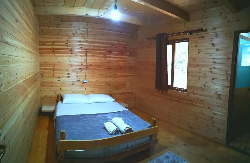 a bedroom with a bed in a wooden cabin at Riverside Komani Lake in Koman