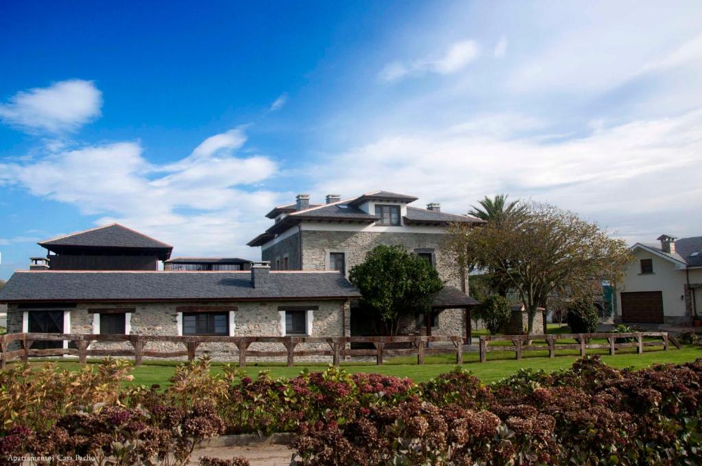 una grande casa in pietra con una recinzione di fronte di Casa Pacho Apartamentos Rurales a Luarca