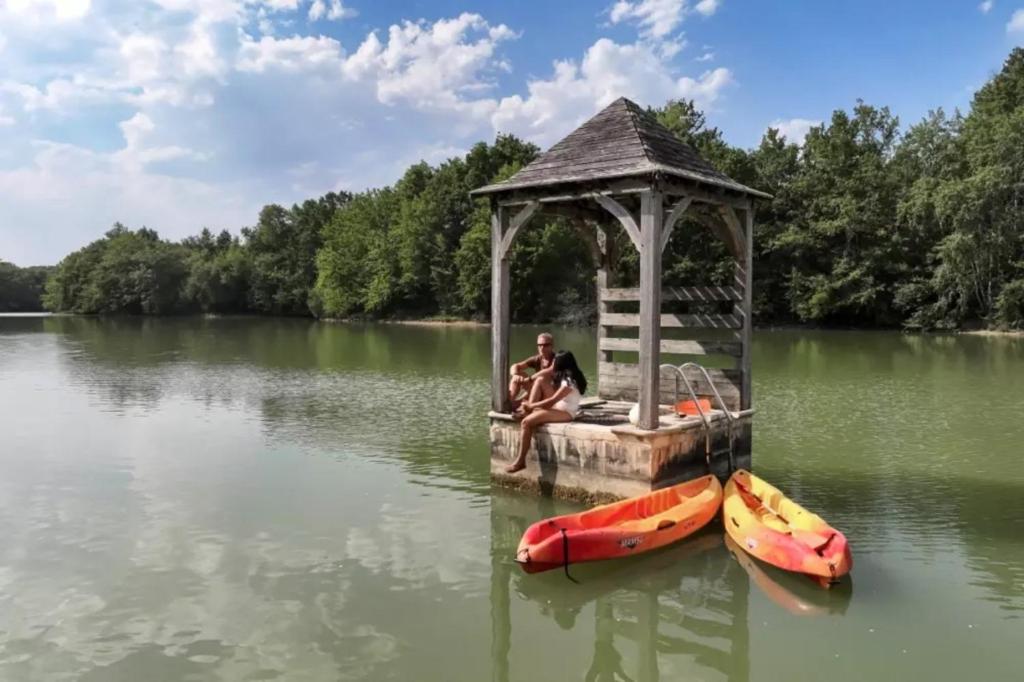 Bretagne-dʼArmagnacにあるMobilhomes Camping Lacs d'Armagnacの湖の見晴台に座る男