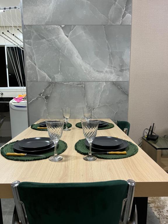 a wooden table with two plates and glasses on it at Loft Home Vila Bella in Cuiabá