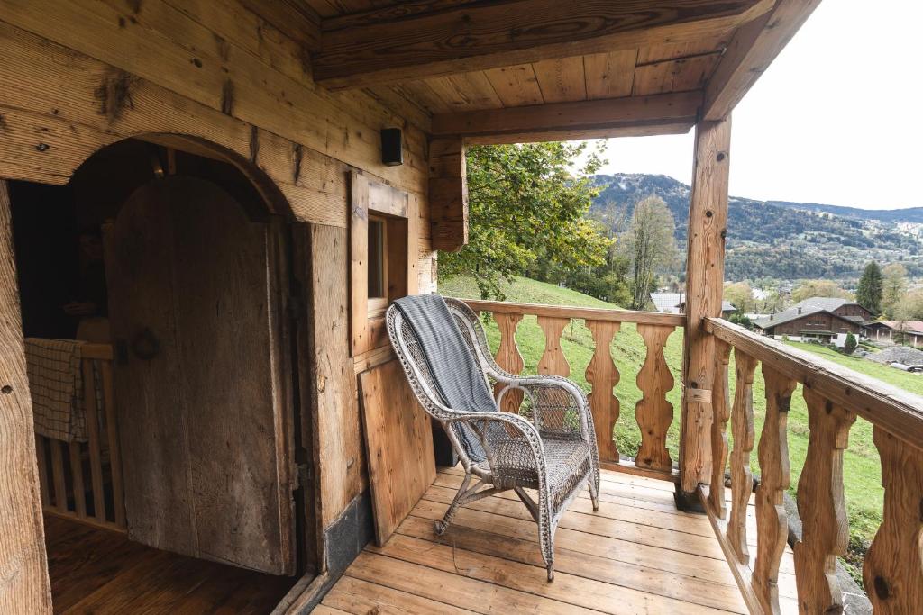 Una silla de mimbre sentada en el porche de una cabaña. en Mazot du Criou - Samoëns, en Samoëns
