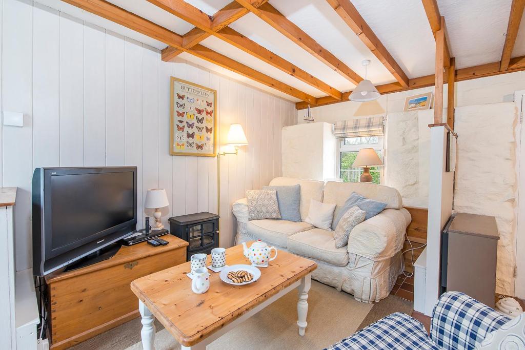 un salon avec un canapé, une télévision et une table dans l'établissement Small Cottage, à Haverfordwest