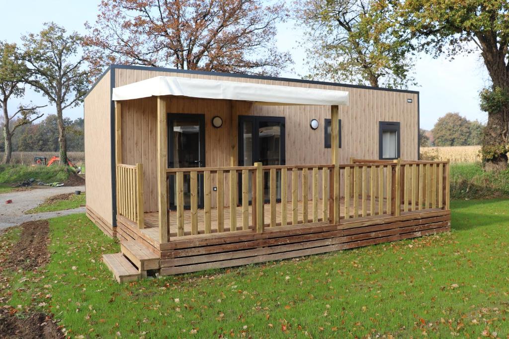 a small house with a fence in the grass at Camping VVF Pontivy in Pontivy