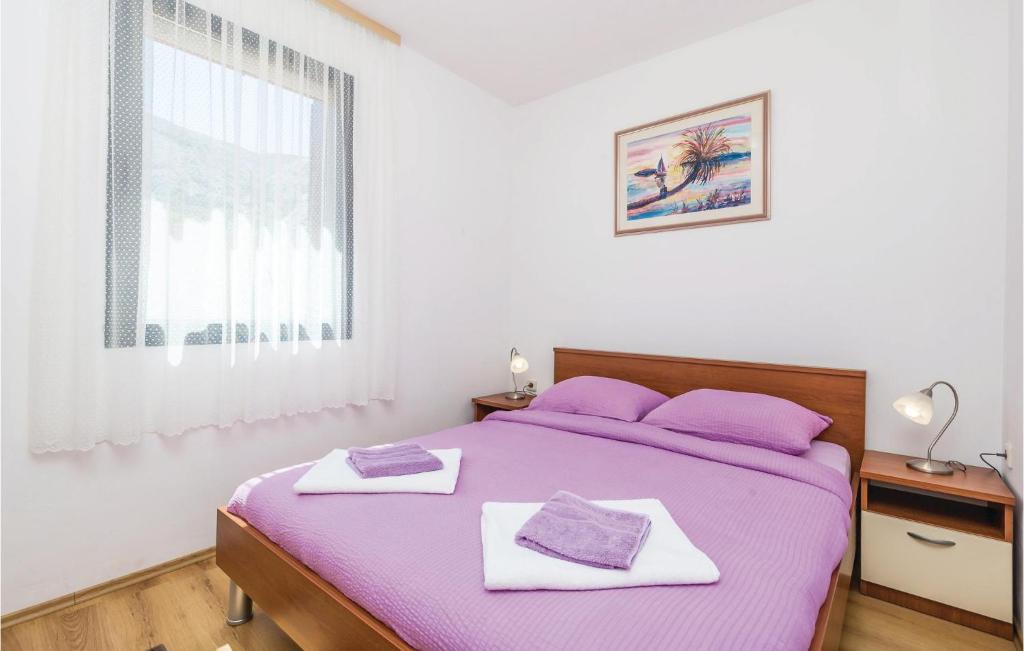 sypialnia z łóżkiem z fioletowymi prześcieradłami i oknem w obiekcie Holiday Home Pag 5 w mieście Pag
