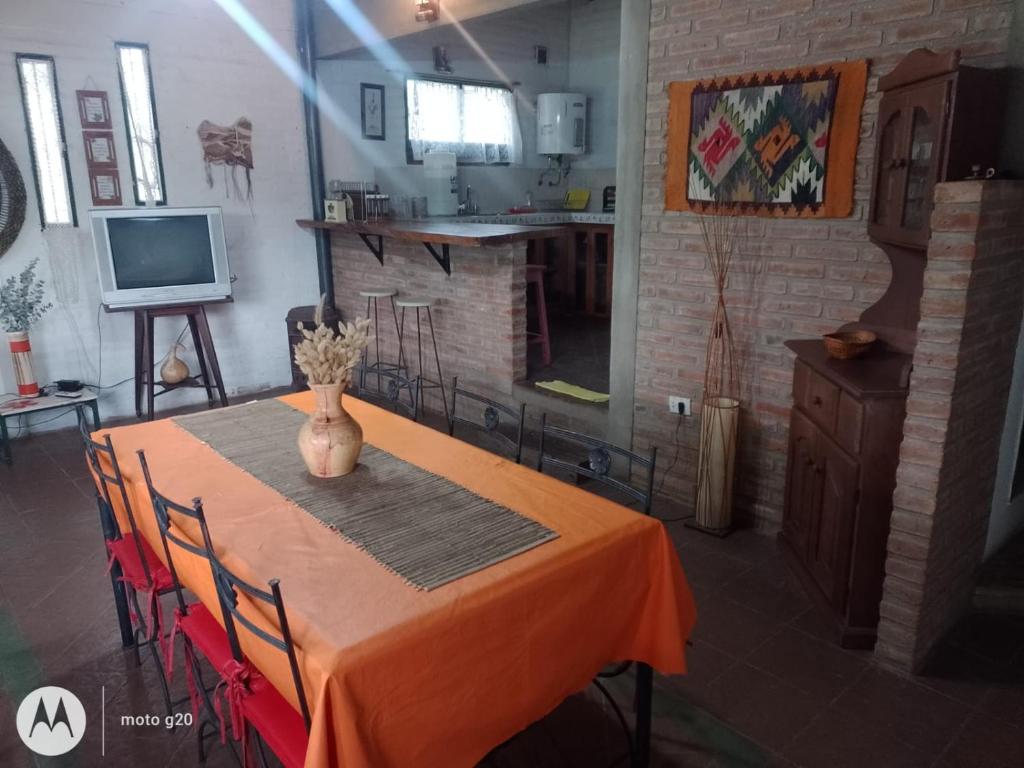 a dining room table with a vase of flowers on it at El Campito casa frente al río in Villa Carlos Paz