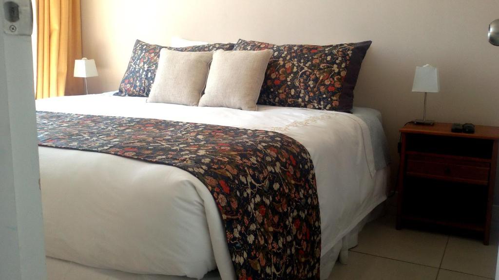 una camera da letto con un letto bianco con una coperta e cuscini floreali di Santiago Neighborhood a Santiago