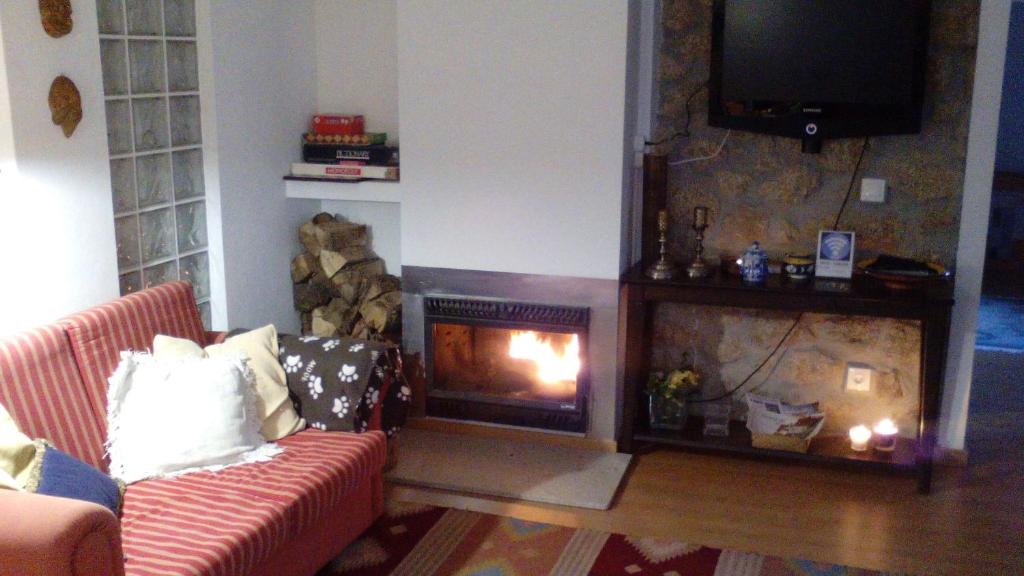 sala de estar con chimenea y TV en Casa da Fonte Grande, en Belmonte