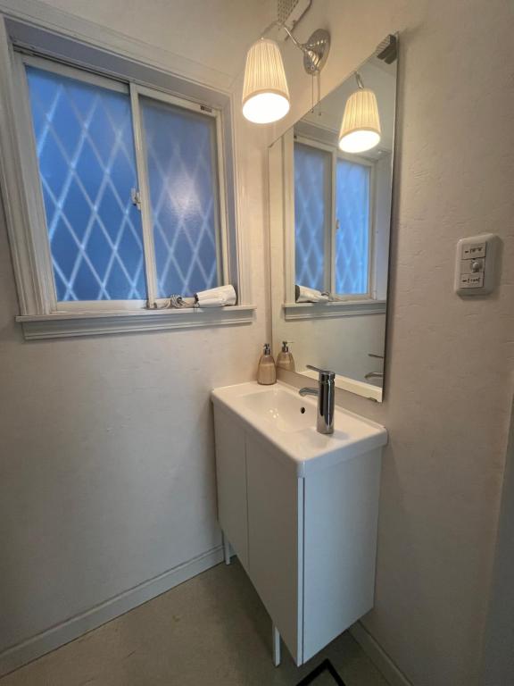 a white bathroom with a sink and a mirror at PROTY Beach House 琵琶湖のコテージ in Minami-komatsu