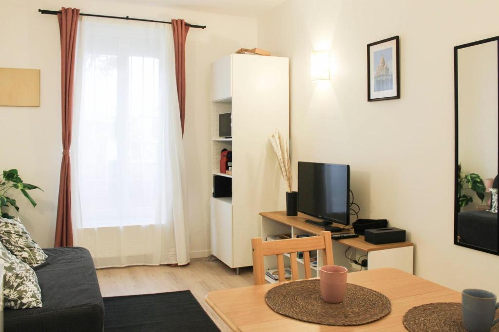 un salon avec une table et une télévision dans l'établissement Charming studio for two at the gates of Paris, à Aubervilliers