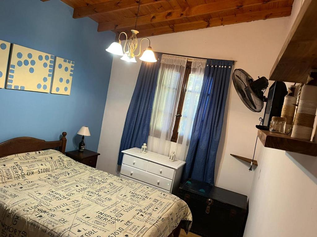 a bedroom with a bed and a window with blue walls at Santa Teresita en el monte in Santa Teresita