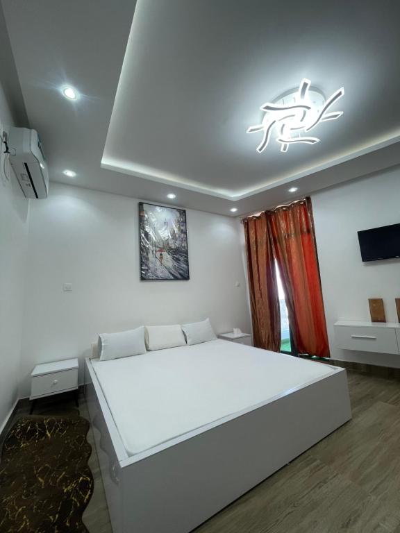a bedroom with a white bed and a sign on the ceiling at BBImmo APPART HOTEL in Dakar