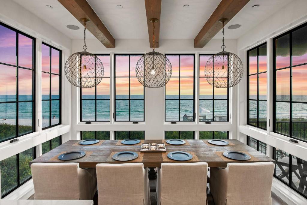 a dining room with a table and chairs and windows at Oasis Cottage & Carriage House in Rosemary Beach