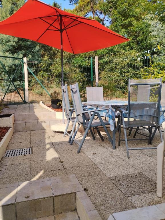 une table et des chaises avec un parasol rouge dans l'établissement Sam Su Fi maison de bord de mer, à La Barre-de-Monts