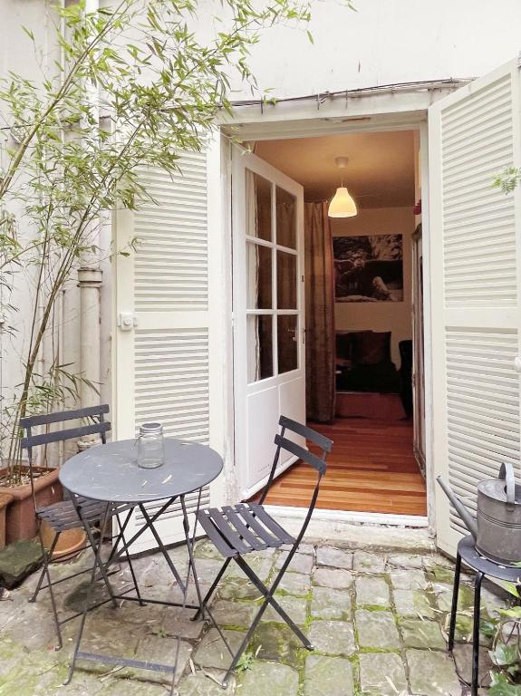 un patio avec une table et des chaises devant une maison dans l'établissement Chic neighborhood charming courtyard studio 7th, à Paris