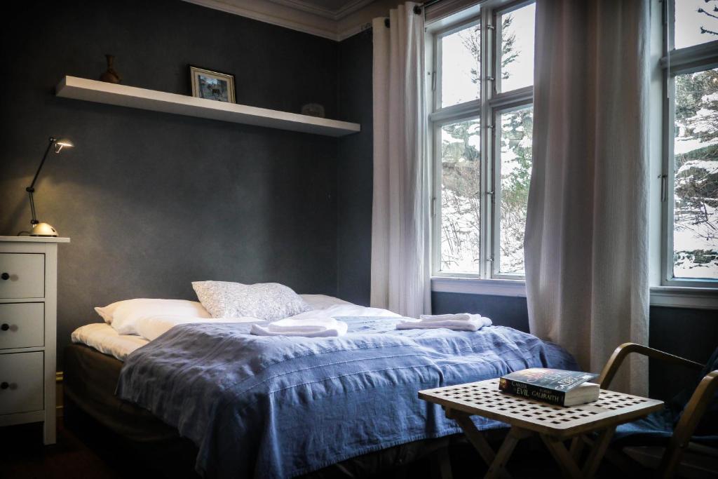 a bedroom with a bed and a table and windows at Amunds Apartment in Bergen