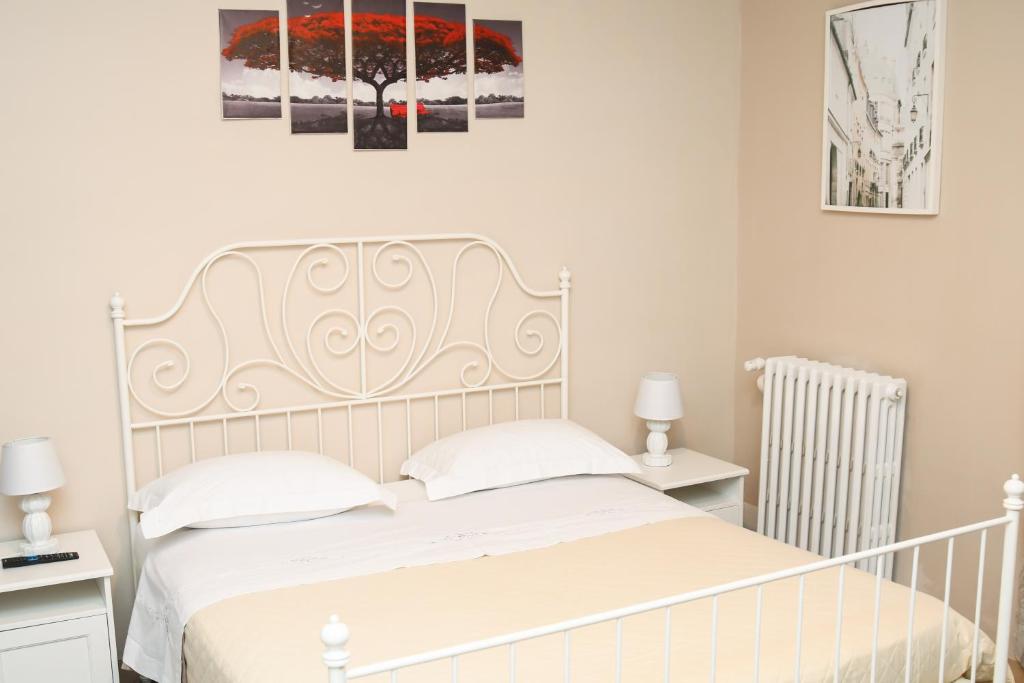 a bedroom with a white bed with two tables and two paintings at La Casa Della Nonna in Montemiletto