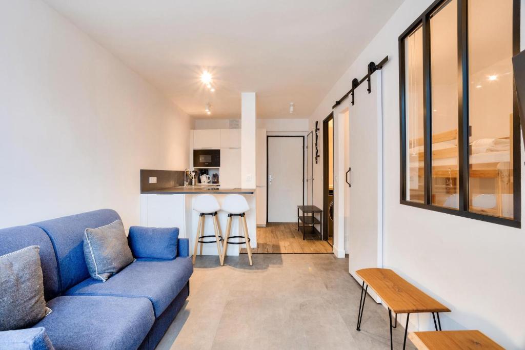 un salon avec un canapé bleu et une cuisine dans l'établissement L'Aiguille - maeva Home - 2 Pièces 4 Personnes Prestige MAE-0414, à Chamonix-Mont-Blanc