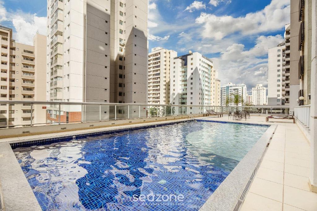 a swimming pool on the roof of a building with tall buildings at Estúdio c/ Piscina em Águas Claras SHT1701 in Águas Claras
