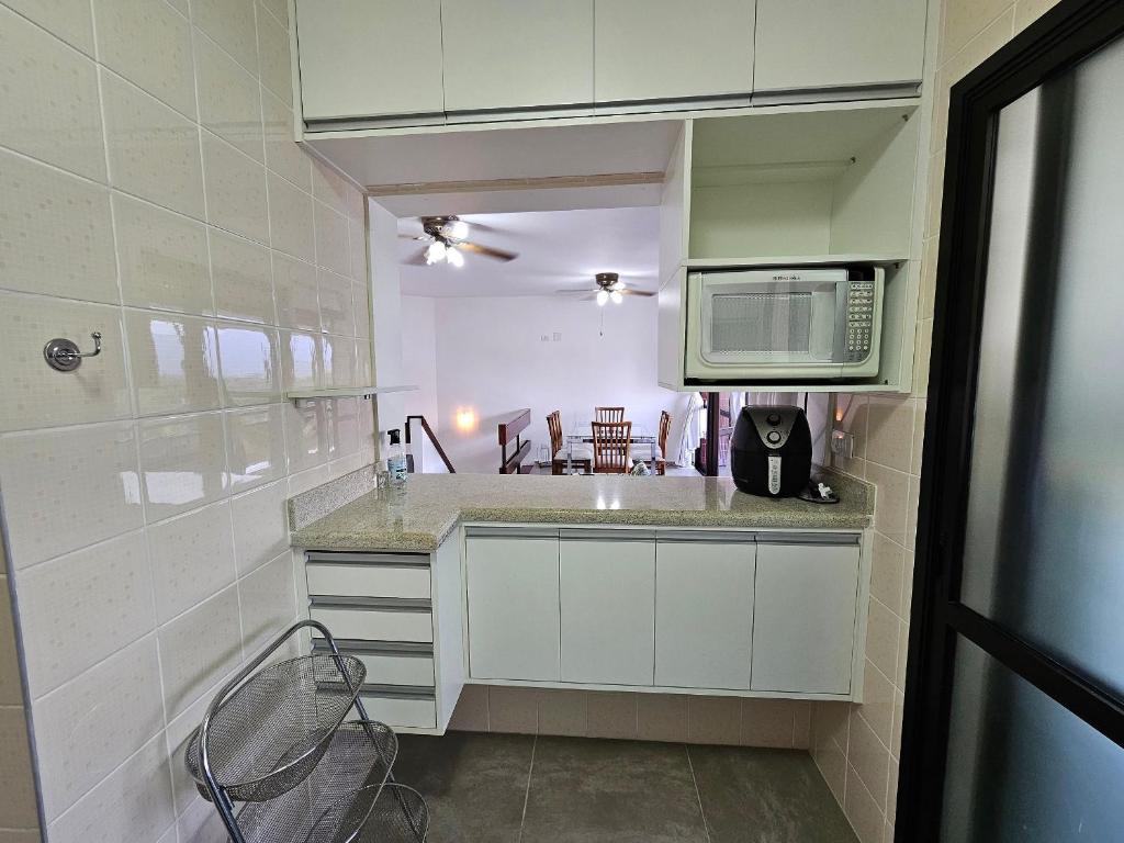 a kitchen with a sink and a microwave at Duplex aconchegante na Riviera - próximo à praia in Bertioga