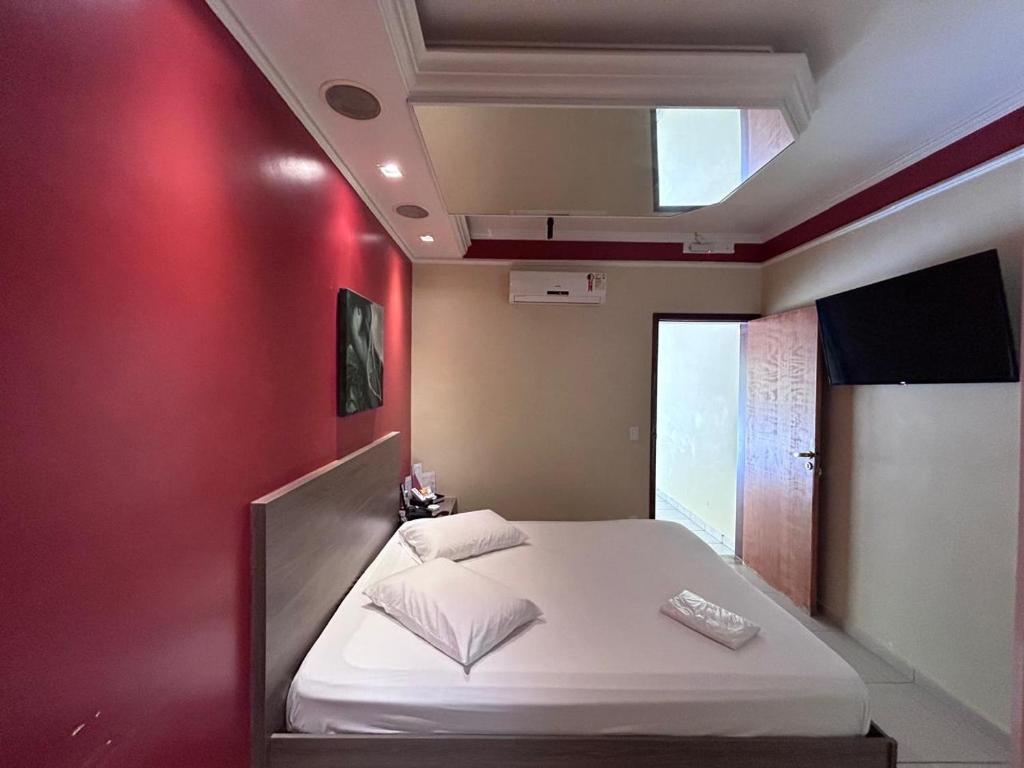 a bed in a room with a red wall at Alpha Motel in Amparo