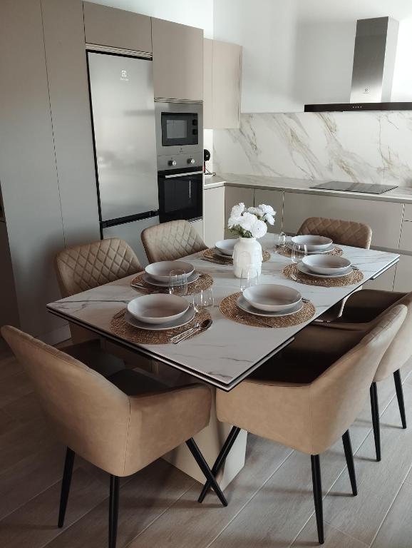 a dining room table with chairs and plates and a kitchen at Quirós Villa Tranquila de Salcedo 1 in La Villa