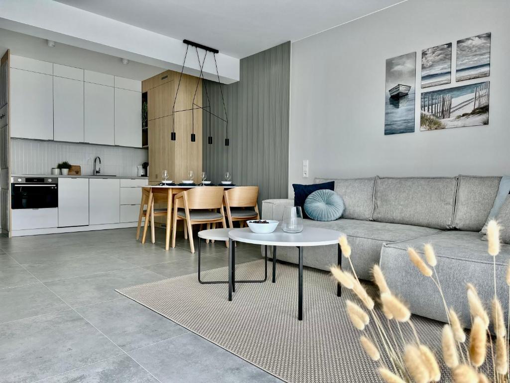 Una sala de estar y una cocina con un sofá y una mesa. en Apartament Scandi, basen & spa, en Rewal