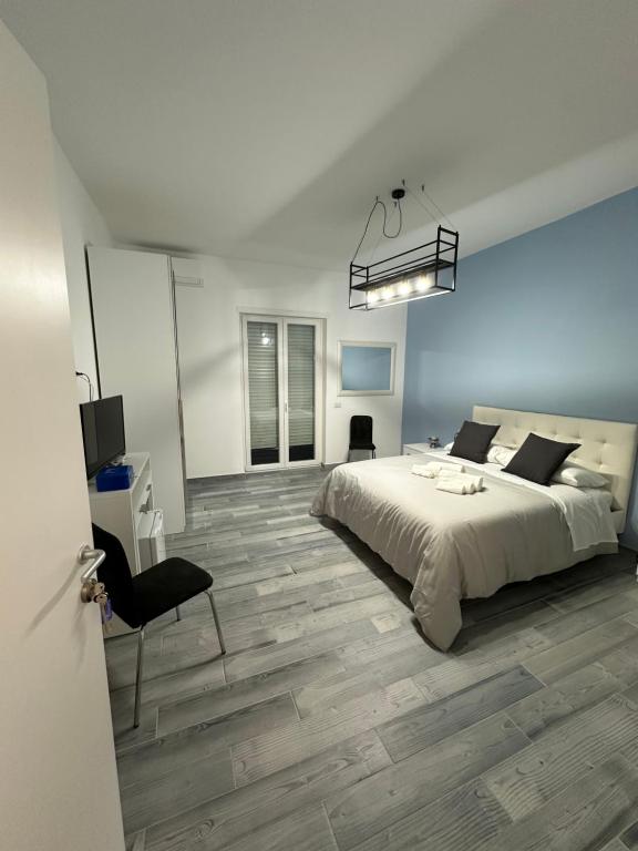 Un dormitorio blanco con una cama y una silla. en La Parthenope suites, en Portici