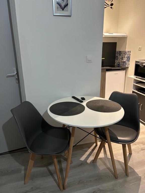 a white table and two black chairs in a kitchen at Studio Capelet in Vichy