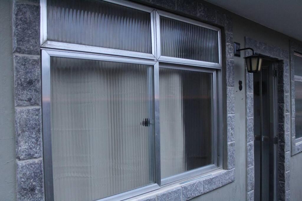 een raam met witte gordijnen op een bakstenen muur bij Kitnet Praiano- Praia de Olaria in Majé