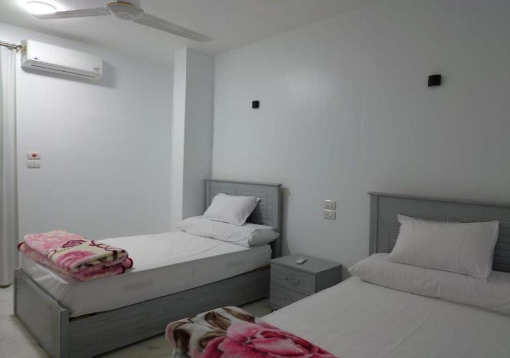 two beds in a white room with avertisement at Alara Hostel ' Only girls ' in Naj‘ al Maḩaţţah