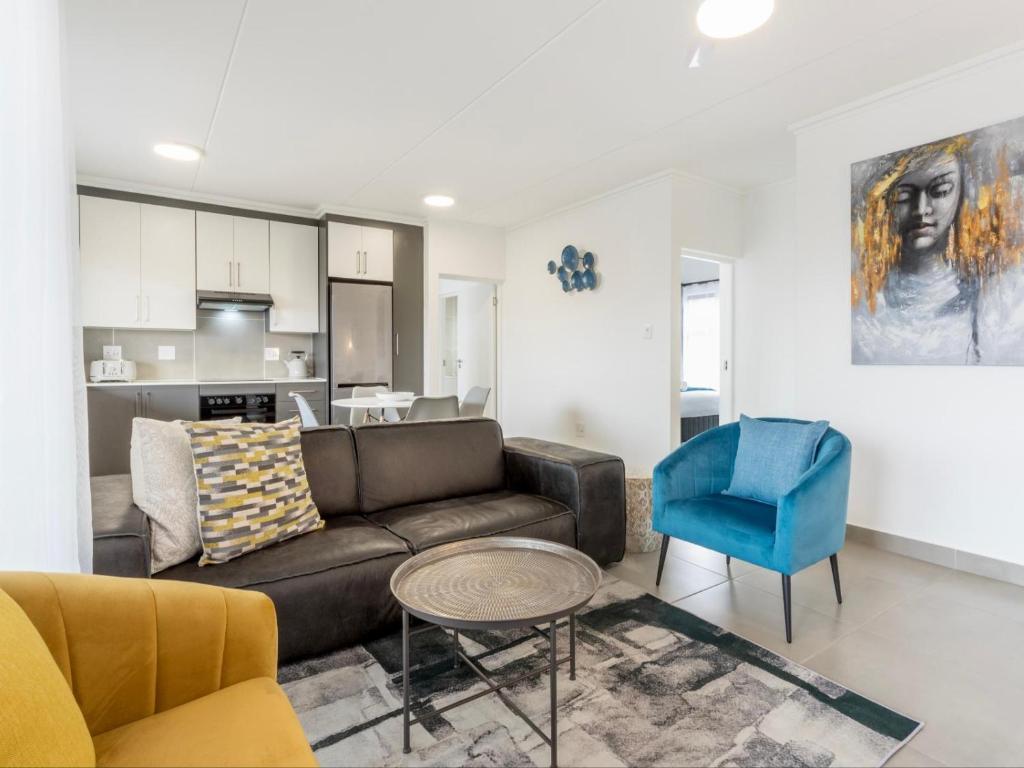 バリートにあるSpacious Ballito Village Apartmentのソファと青い椅子のあるリビングルーム