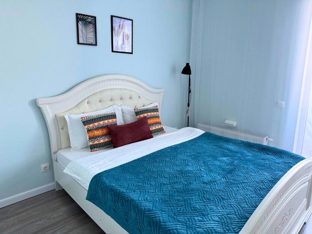a blue bedroom with a white bed with pillows at Nexpo City уютные апартаменты возле ЭКСПО in Prigorodnyy