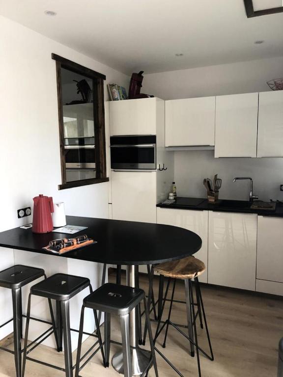 une cuisine avec des placards blancs, une table noire et des tabourets dans l'établissement Résidence Res.de L Oisans - APPARTEMENT ALPE D'HUEZ PROCHE CENTRE STATION MAE-2451, à Huez