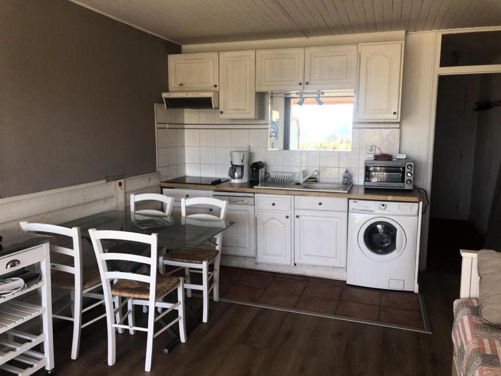 une cuisine avec des armoires blanches et une table et des chaises dans l'établissement Résidence Olympiades B - APPARTEMENT ALPE D'HUEZ CENTRE STATION MAE-2581, à Huez