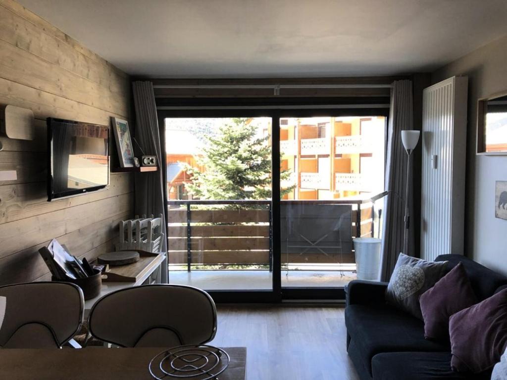 d'un salon avec un canapé et une vue sur un balcon. dans l'établissement Résidence Helios - STUDIO ALPE D'HUEZ CENTRE STATION AVEC PARKING COUVERT MAE-2761, à Huez